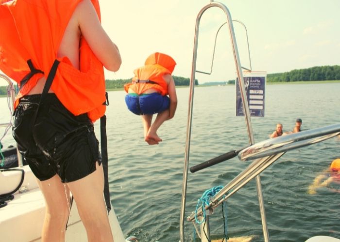 Chłopak skacze w kamizelce do wody